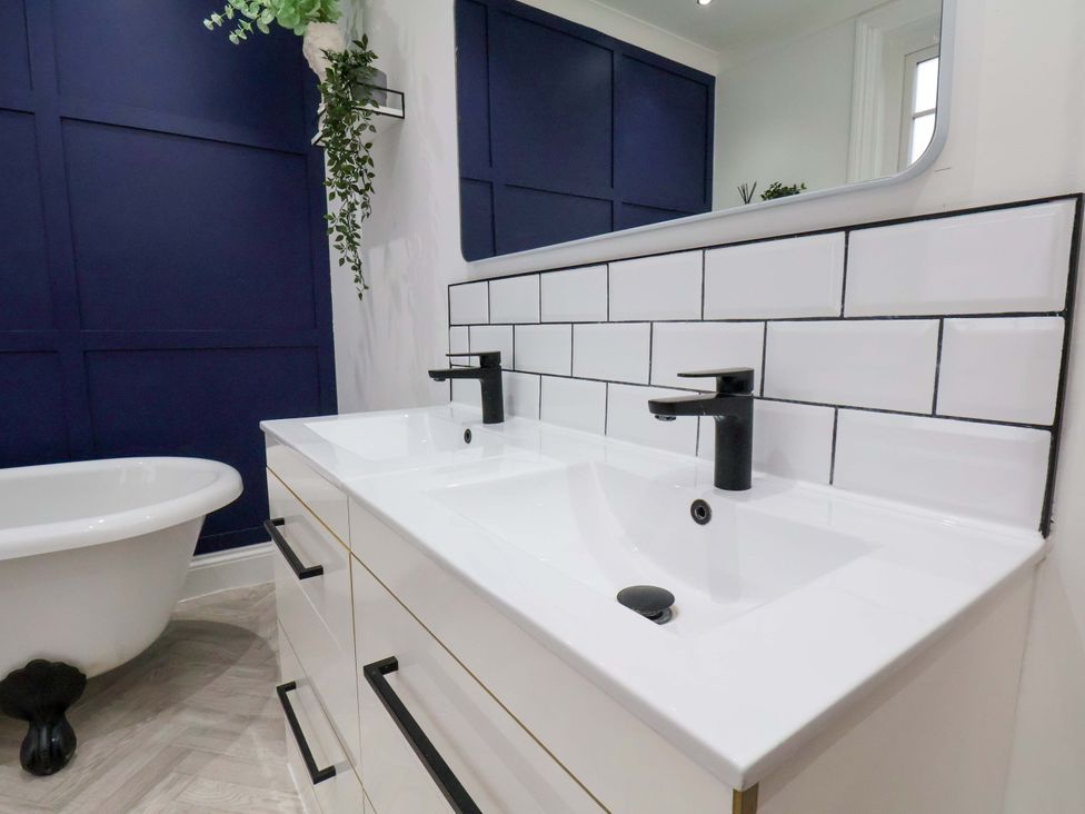 A bathroom with a sink, tub, and wall tiles at 59 Moorland Road Scarborough
