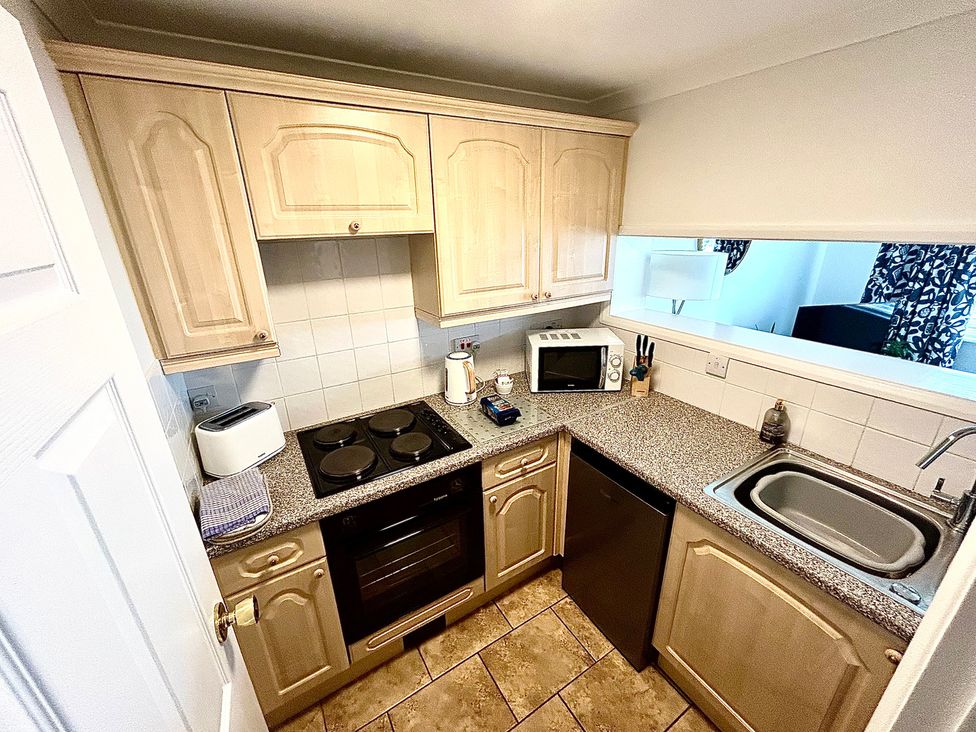 A kitchen with cabinets, stove, oven, sink, and microwave at 1 Chatsworth Riverscape Apartments in Newquay