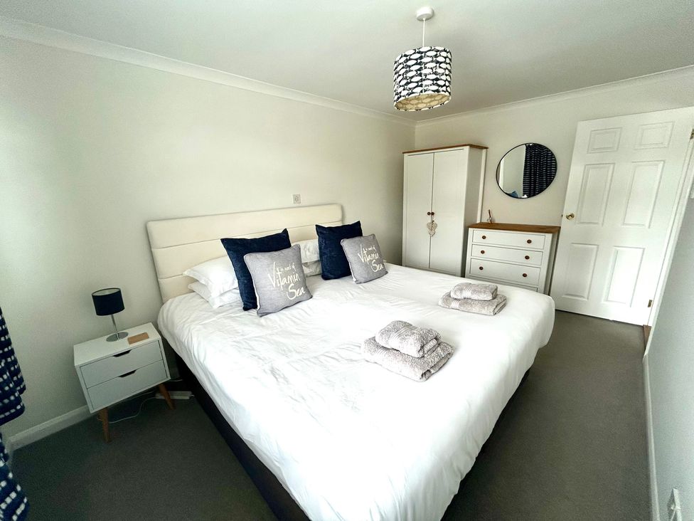 A bedroom with a bed, bedside table, wardrobe, and mirror at 1 Chatsworth Riverscape Apartments Newquay