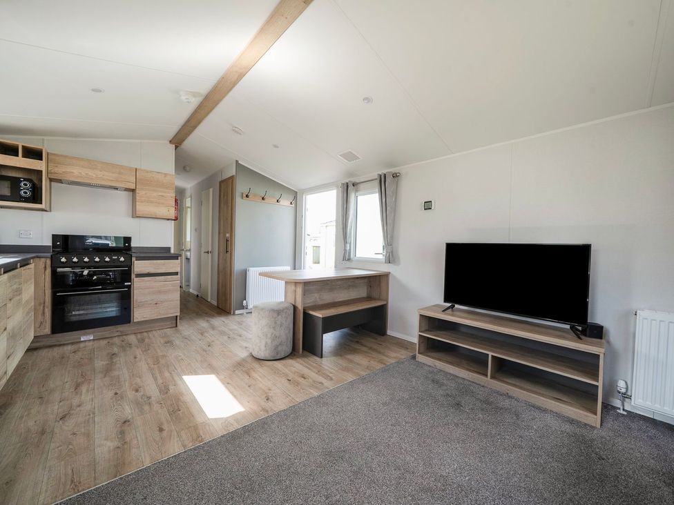 A living room with a kitchen unit and television at Billy’s Way - Hayling Island Holiday Park
