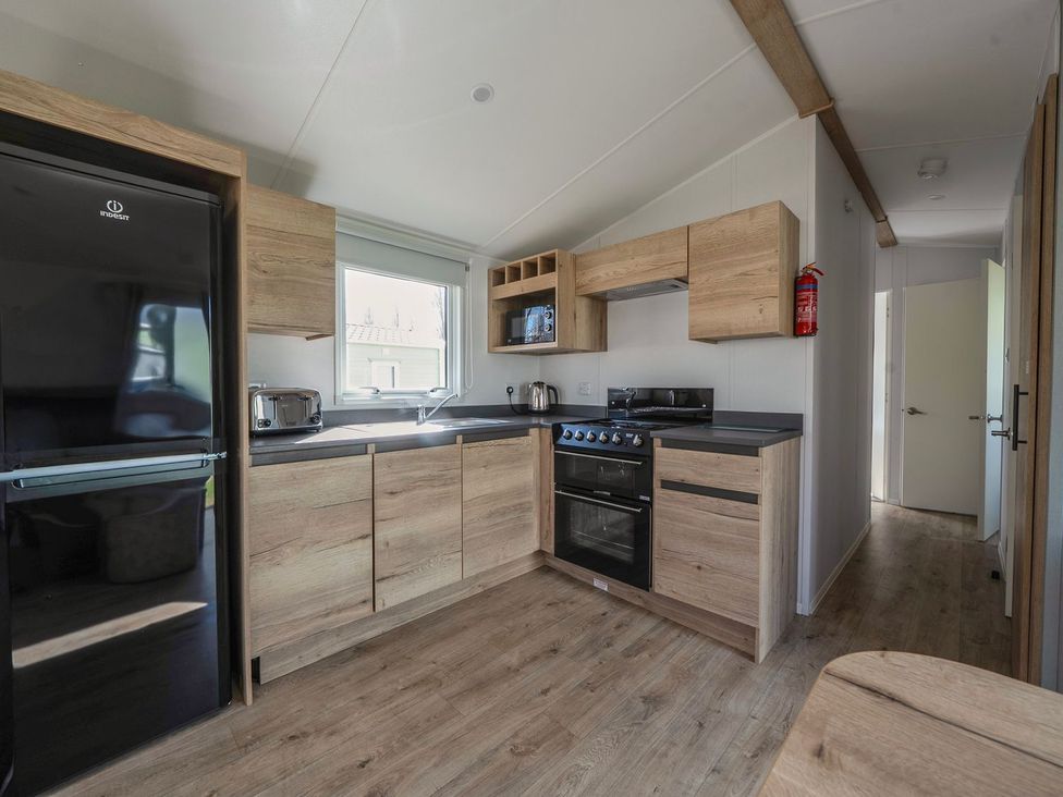 A kitchen with wooden cabinets and appliances at Billy’s Way - Hayling Island