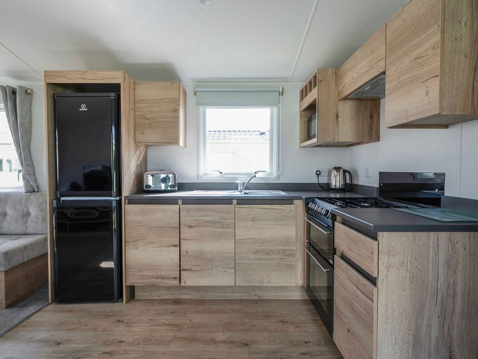 A kitchen with wooden cabinets and appliances at Billy’s Way - Hayling Island
