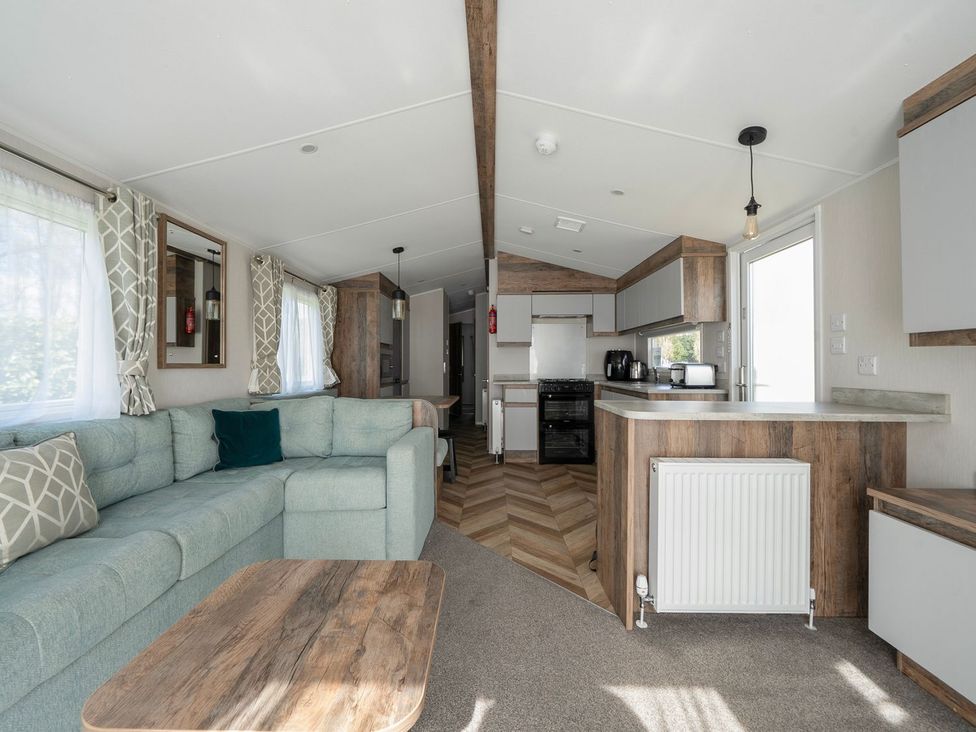 A living room with a sofa and kitchen area at Blue Flag Shores - Hayling Island