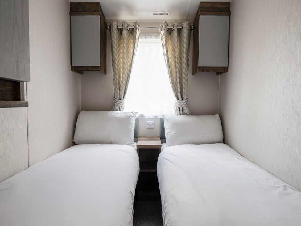 A bedroom with two single beds and curtains at Blue Flag Shores - Hayling Island