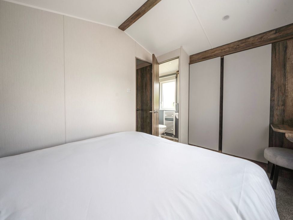 A bedroom with a bed and a mirror at Blue Flag Shores - Hayling Island Holiday Park