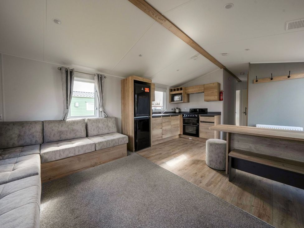 A living room with a sofa and kitchen area at The Splash Pad - Billing Aquadrome