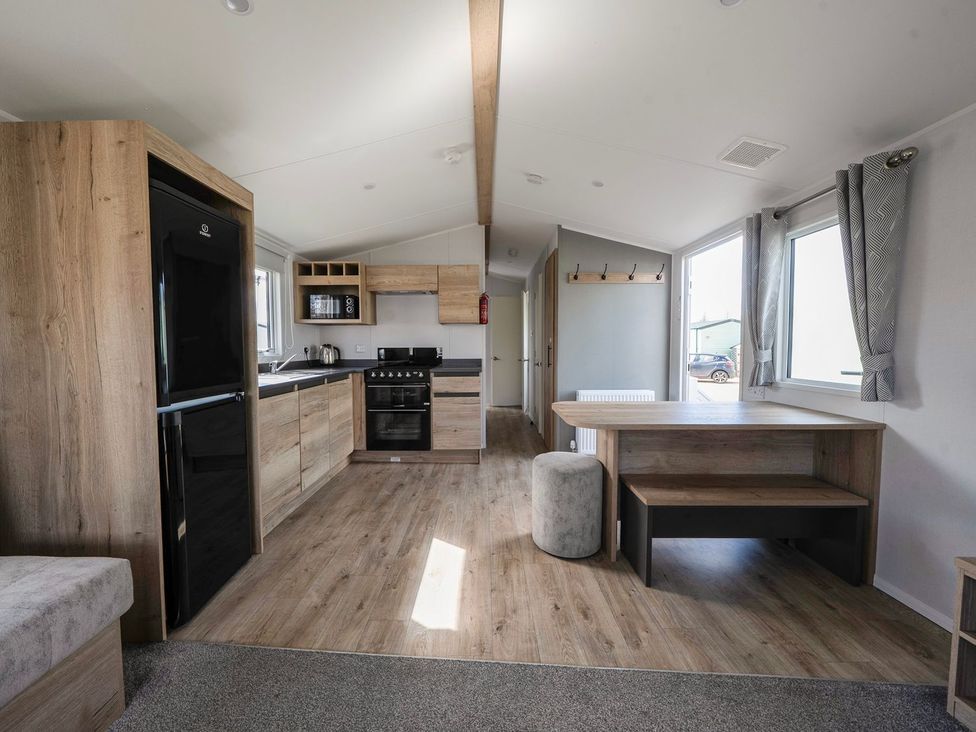 A kitchen with a fridge, oven, and dining area at The Splash Pad - Billing Aquadrome
