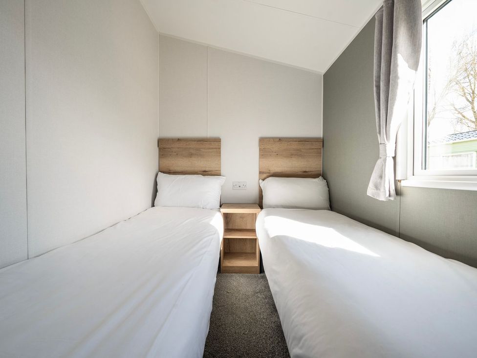 A bedroom with twin beds and a nightstand at The Splash Pad - Billing Aquadrome