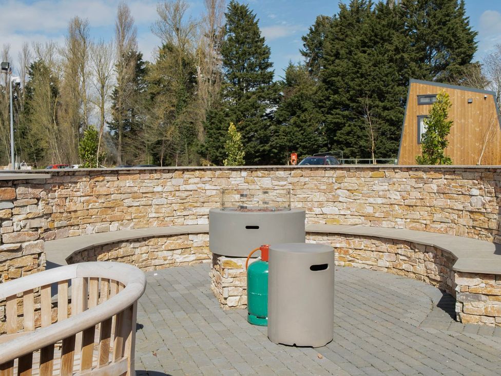 An outdoor seating area with a stone wall and benches at The Splash Pad - Billing Aquadrome