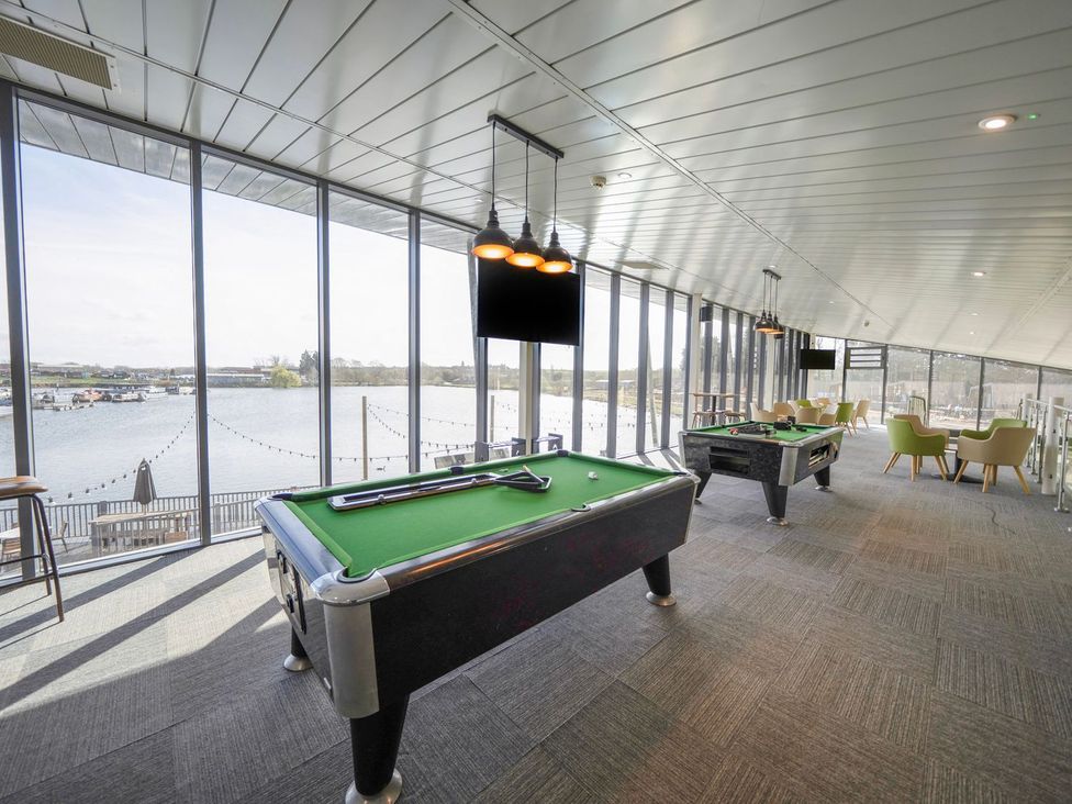 A games room with pool tables and seating overlooking the water at The Splash Pad - Billing Aquadrome