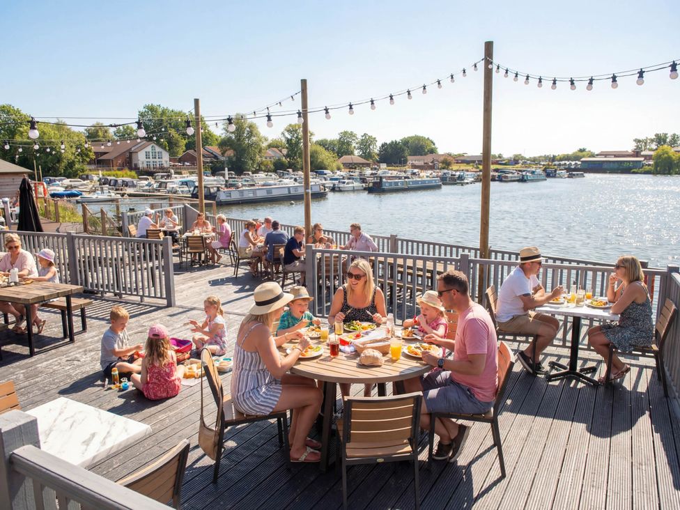 An outdoor seating area with people dining near water at The Splash Pad - Billing Aquadrome