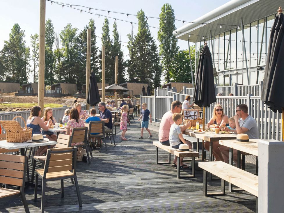 An outdoor dining area with tables and people at Serenity Shores - Billing Aquadrome