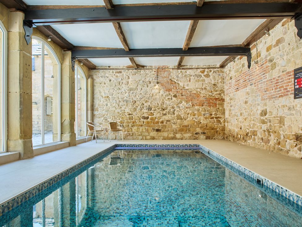 An indoor pool with stone walls and a chair at The Card House in Hopton