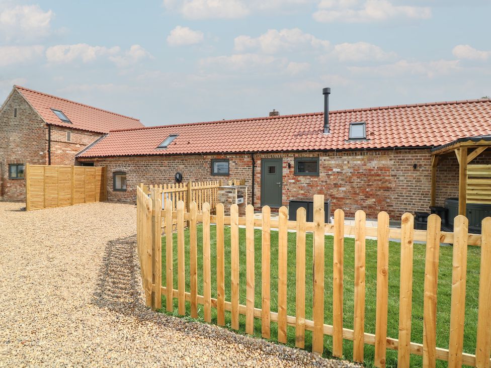 An outdoor view of a barn with a fence and grass at Buzzard Barn in Woodhall Spa