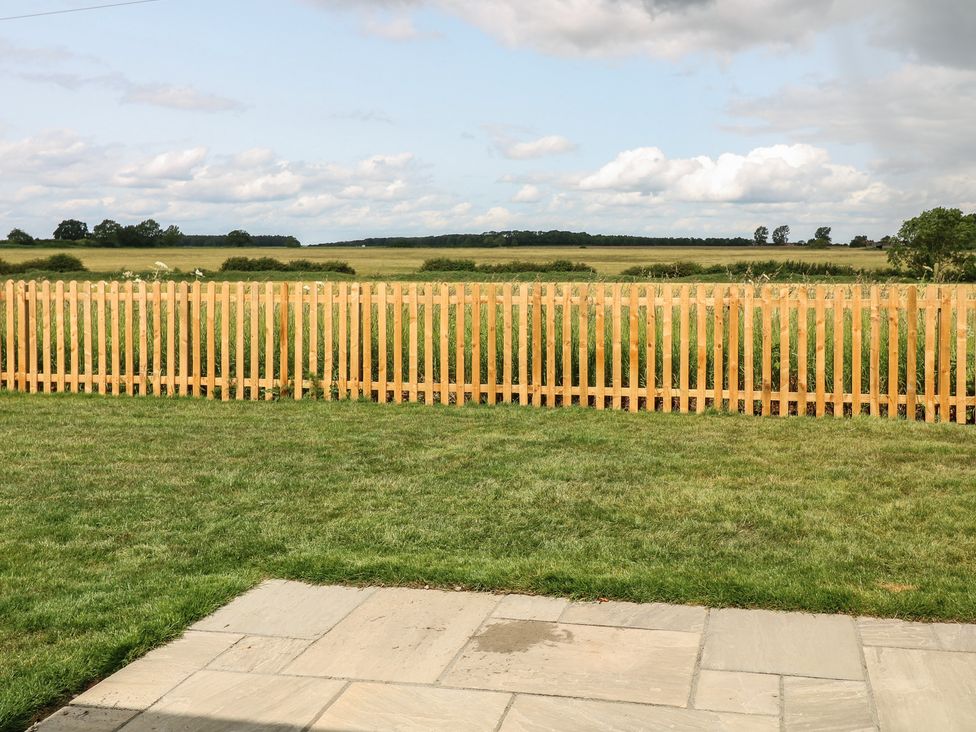 A garden with a wooden fence and grass at Buzzard Barn in Woodhall Spa