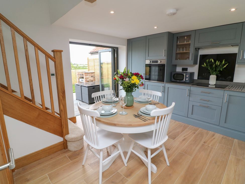 A kitchen with a dining area and modern appliances at Buzzard Barn Woodhall Spa