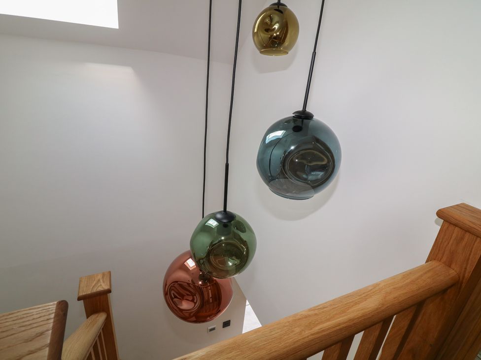 Hanging light fixtures and wooden railing in a staircase at Buzzard Barn Woodhall Spa
