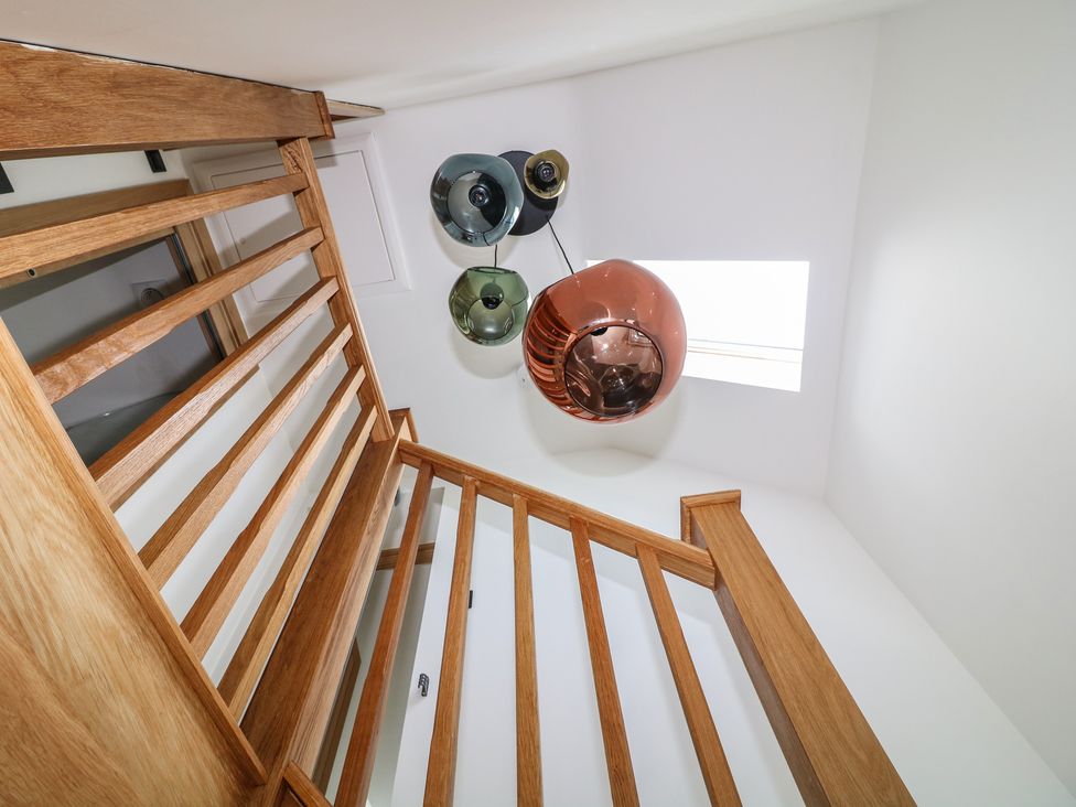 A staircase with wooden railing and light fixtures at Buzzard Barn in Woodhall Spa
