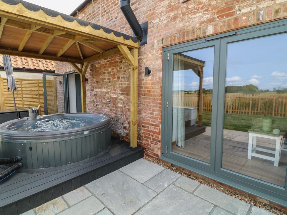 An outdoor area with a hot tub and sliding glass doors at Buzzard Barn in Woodhall Spa