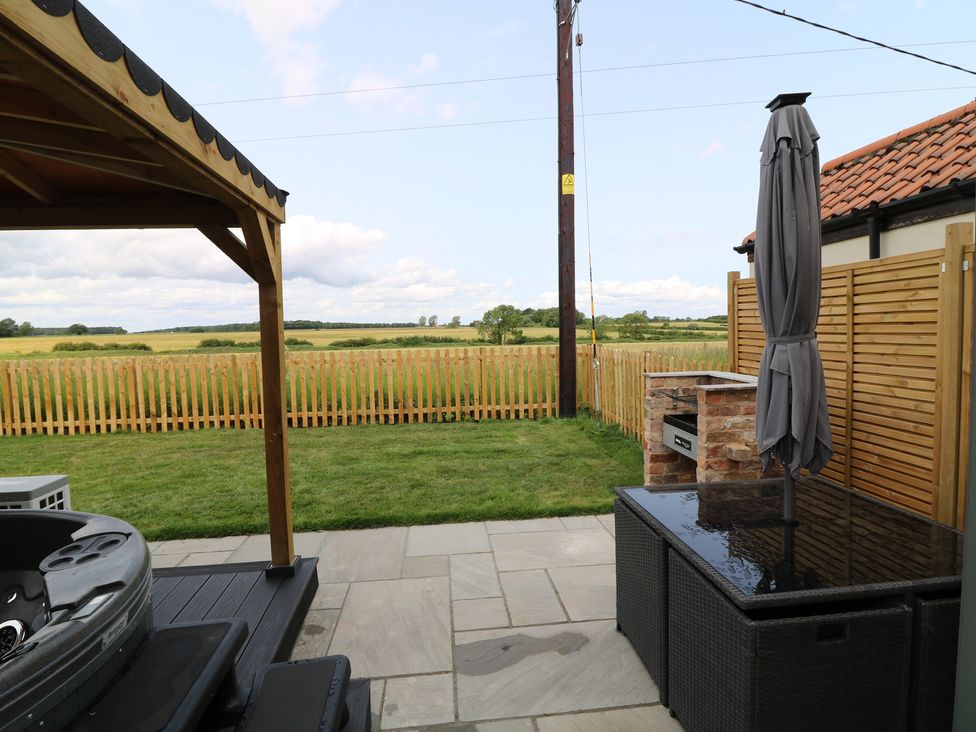 A garden with a hot tub and outdoor furniture at Buzzard Barn Woodhall Spa