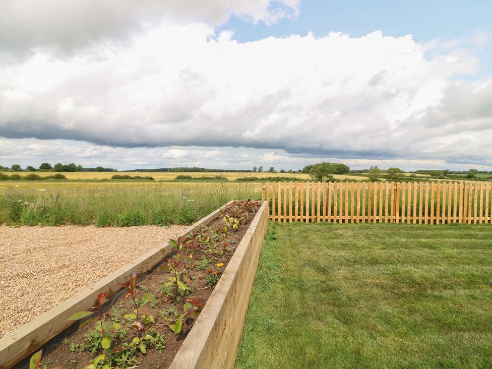 A garden with a raised bed and a fence at Buzzard Barn in Woodhall Spa