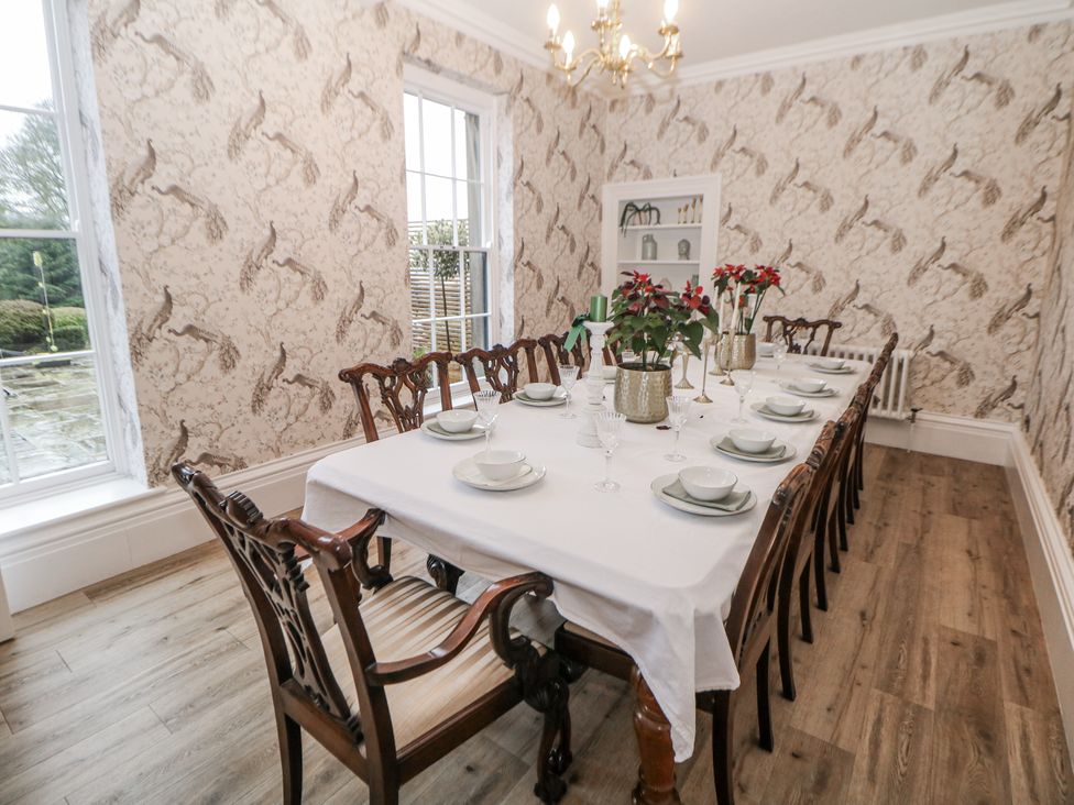 A dining room with a large table set with tableware at Hallfield Hall in Shirland near Higham