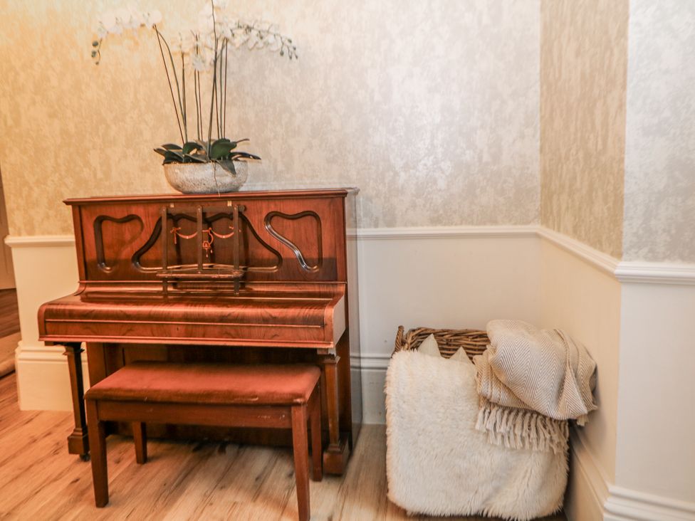 A piano with a bench and a basket in the living room at Hallfield Hall Shirland near Higham