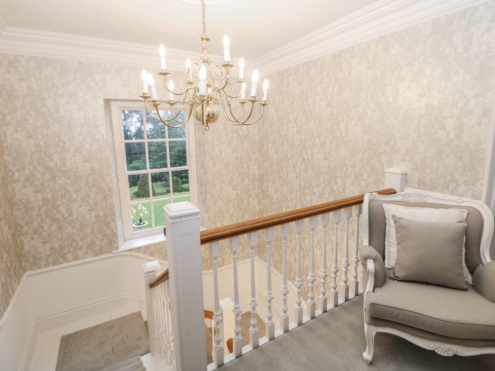 A staircase with a chandelier and window at Hallfield Hall in Shirland near Higham