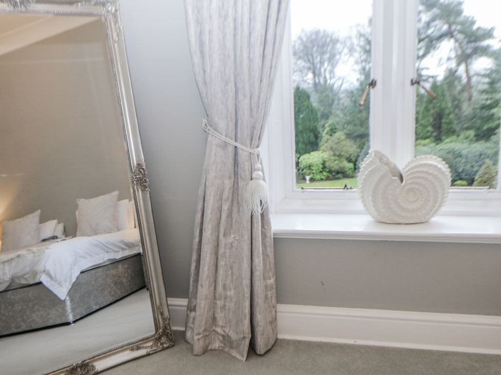 A bedroom with a mirror and decorative object on the window sill at Hallfield Hall Shirland near Higham