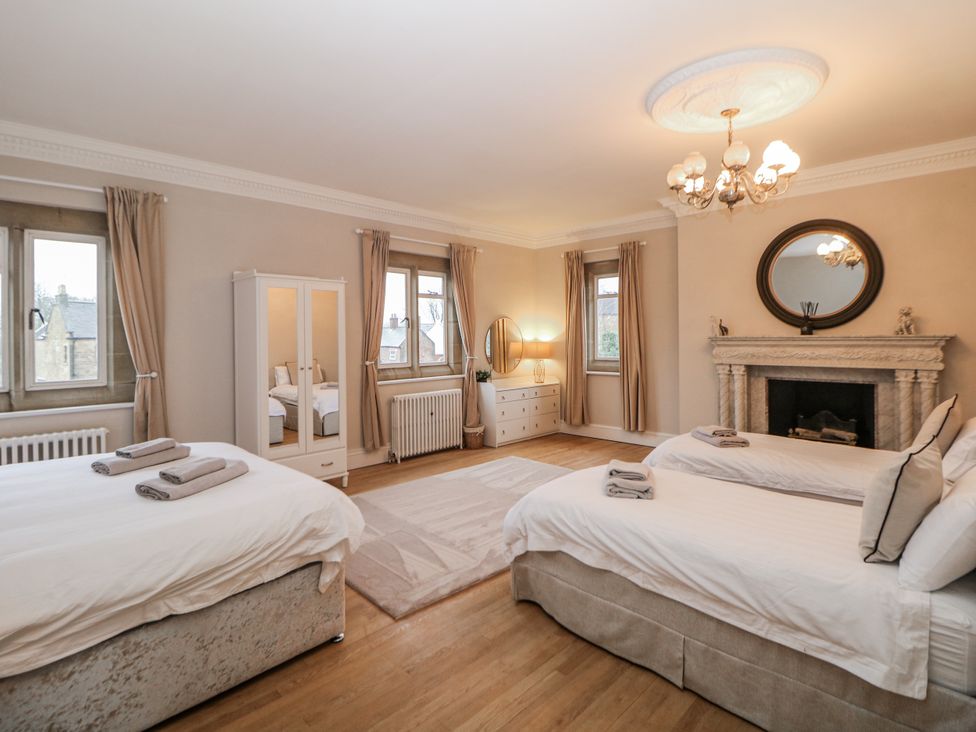 A bedroom with two beds, a dresser, and a fireplace at Hallfield Hall in Shirland near Higham