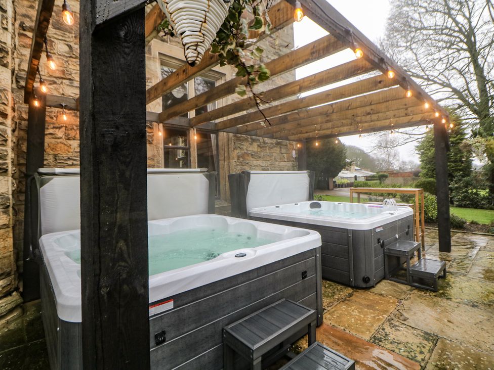 Hot tubs under a wooden pergola in a garden at Hallfield Hall in Shirland near Higham