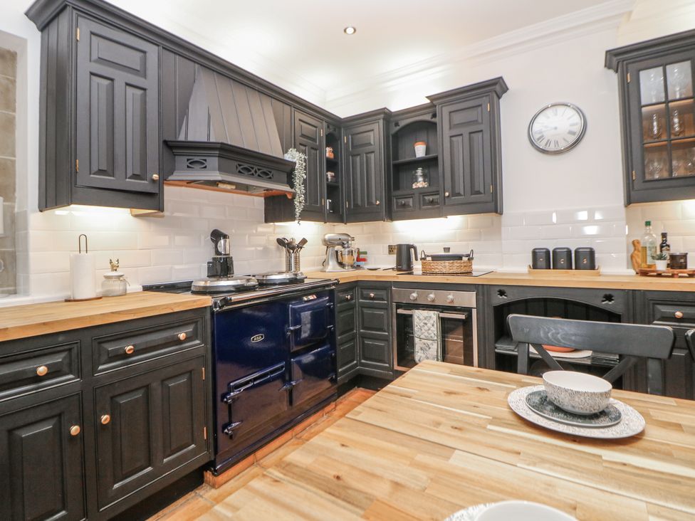 A kitchen with black cabinets and a blue stove at Hallfield Hall Cottage in Shirland