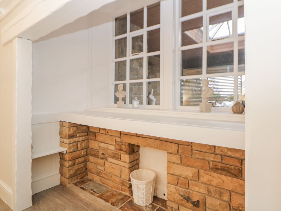 A living room with a stone wall and windows at Hallfield Hall Cottage in Shirland