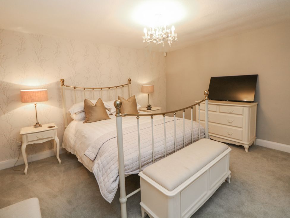 A bedroom with a bed and television at Hallfield Hall Cottage Shirland