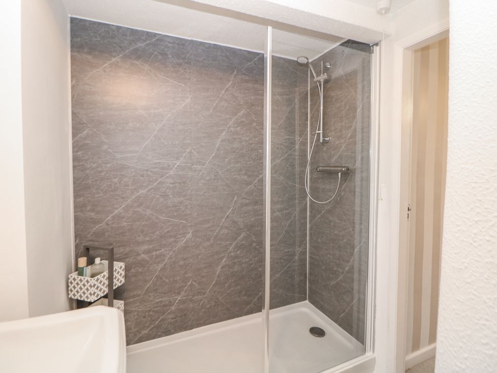 A bathroom with a shower and accessories at Hallfield Hall Cottage in Shirland