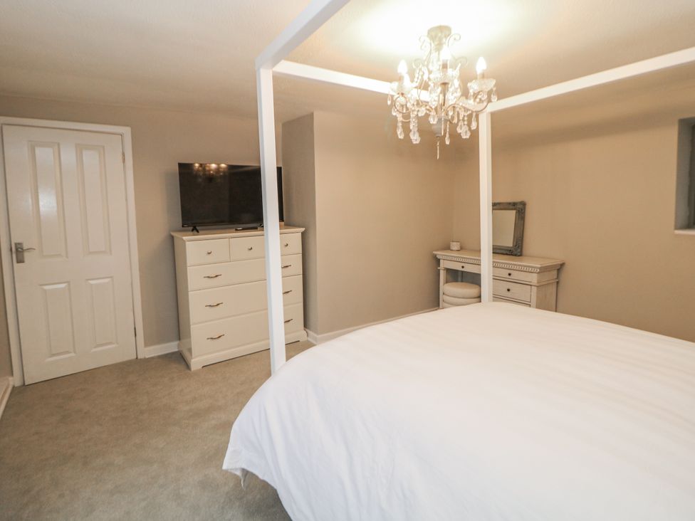 A bedroom with a four-poster bed and a television at Hallfield Hall Cottage in Shirland
