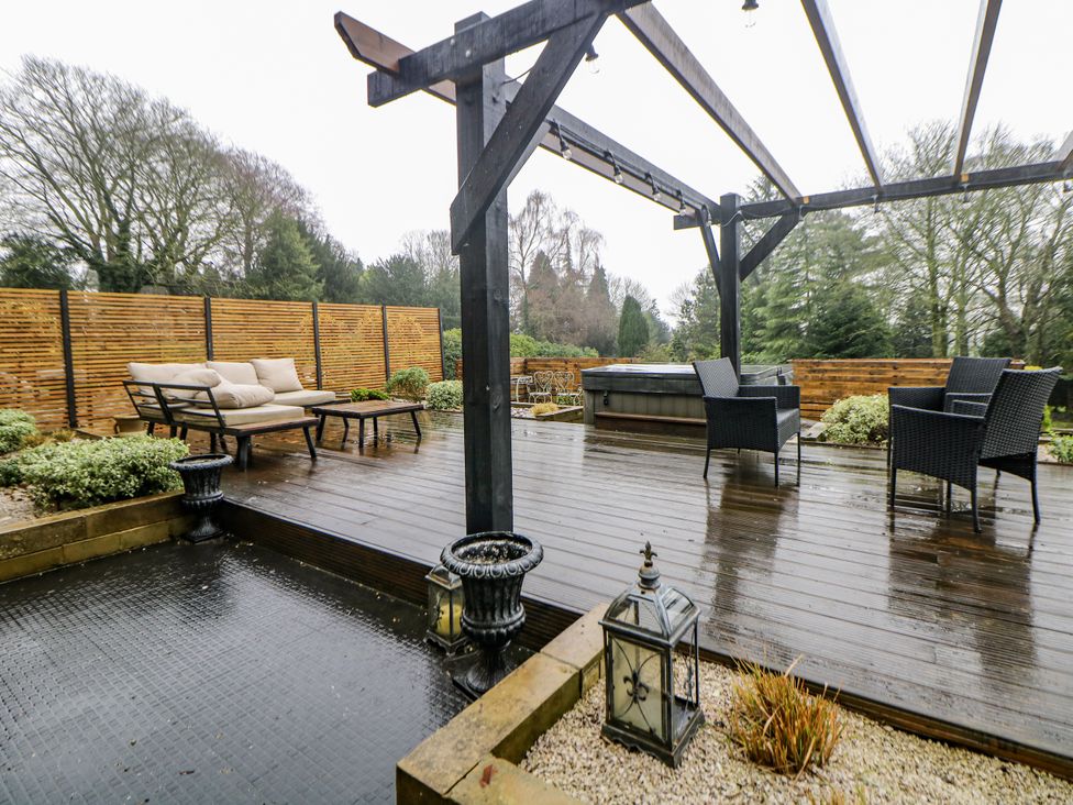 An outdoor space with decking, seating, hot tub, and planters at Hallfield Hall Cottage in Shirland
