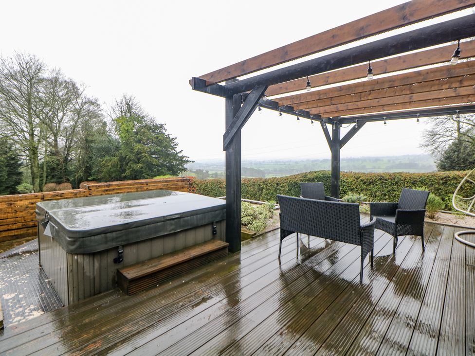 An outdoor area with a hot tub and seating at Hallfield Hall Cottage in Shirland