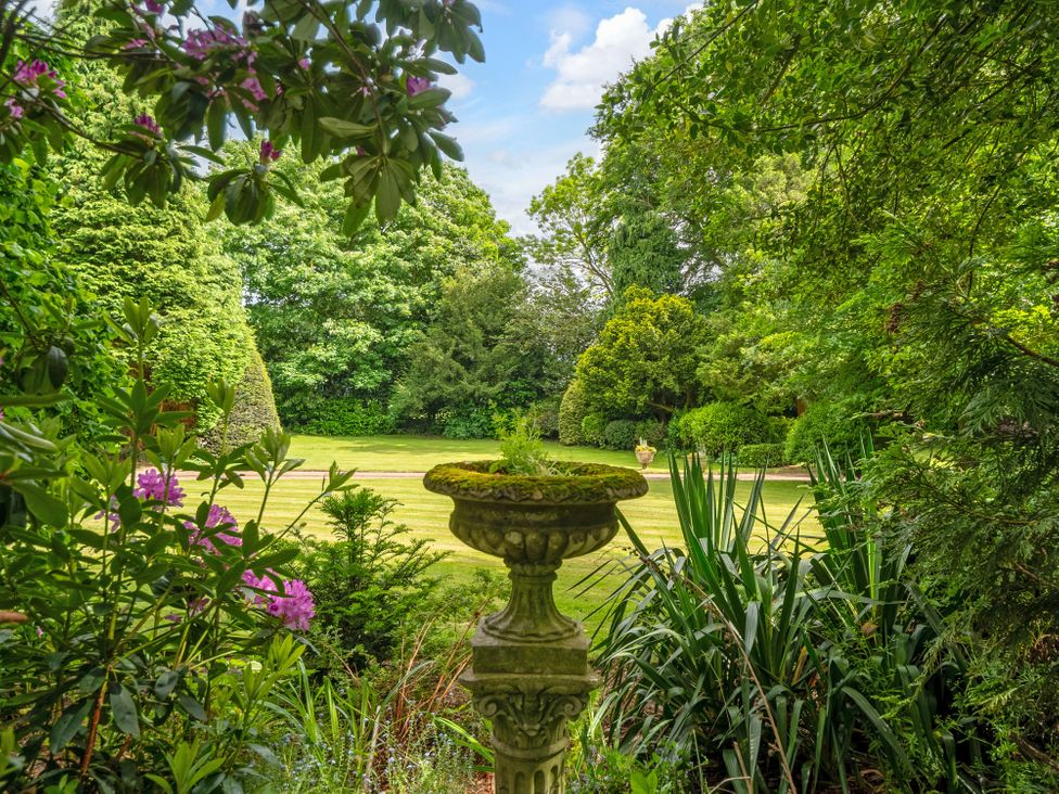 A garden view with an ornamental urn at Hallfield Hall Cottage in Shirland