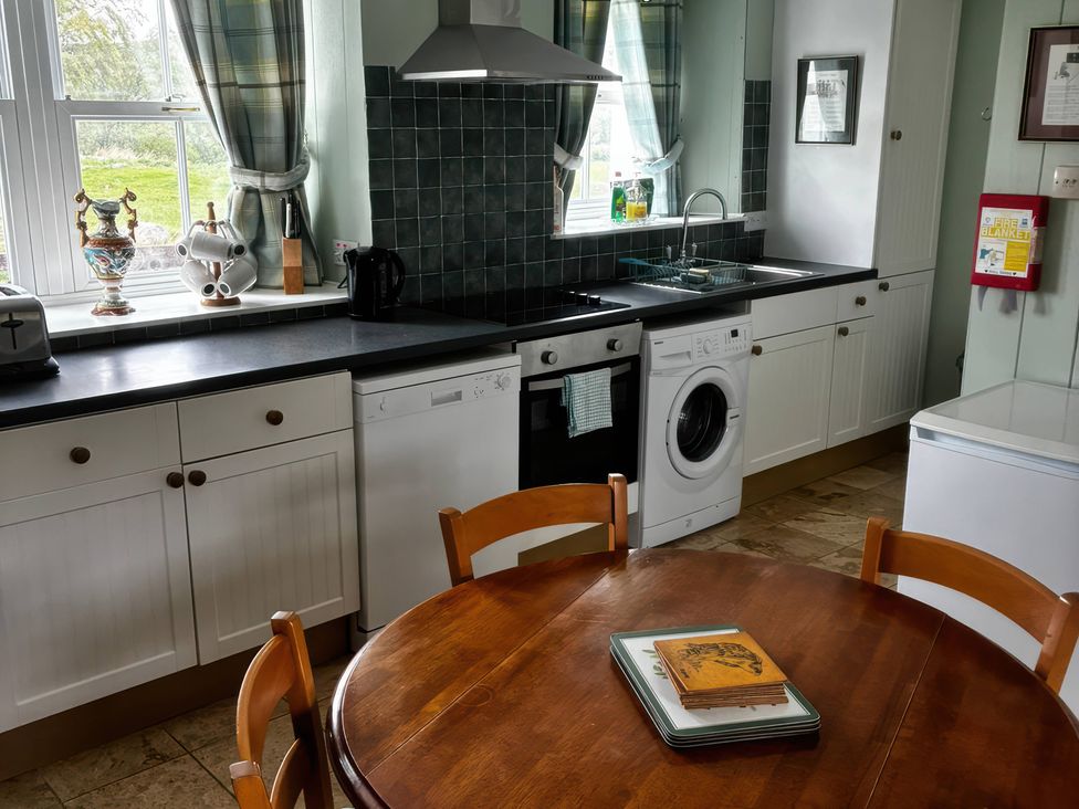 A kitchen with a table and appliances at Strathnoon in Clune near Carrbridge