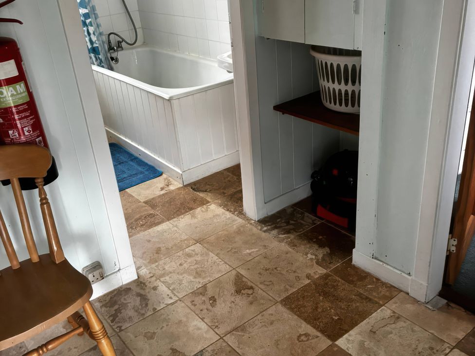 A bathroom with a bathtub and washing basket at Strathnoon in Clune near Carrbridge