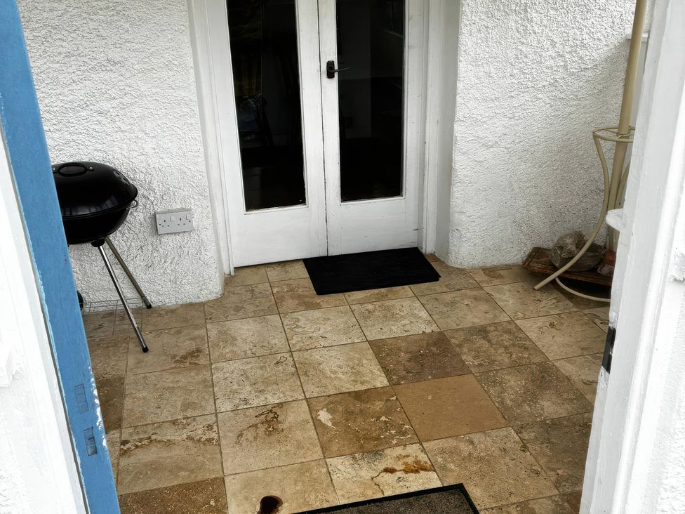 An outdoor entryway with double doors and a barbecue at Strathnoon in Clune near Carrbridge
