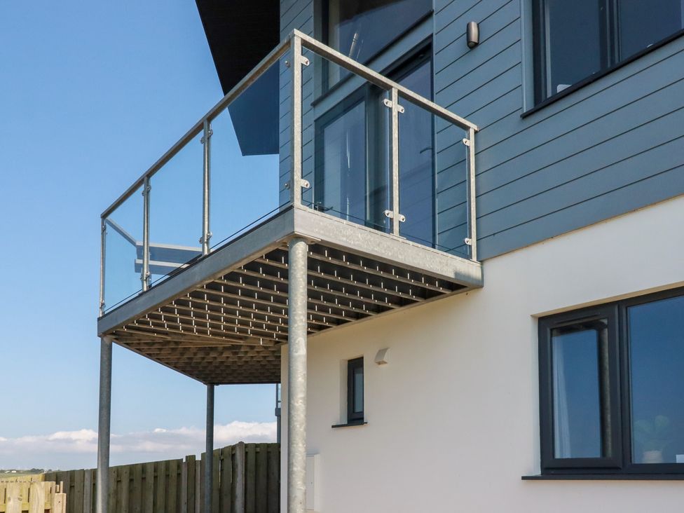 A balcony with a glass railing attached to a house at Jacana in Perranporth