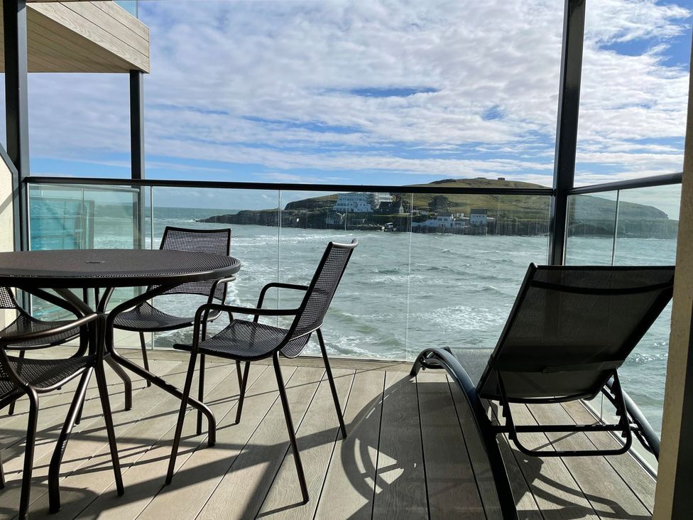 A balcony with a table and chairs overlooking the water at Apartment 12, Burgh Island Causeway Bigbury-On-Sea