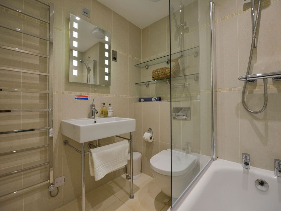 A bathroom with washbasin, toilet, shower, and shelves at Apartment 12, Burgh Island Causeway Bigbury-On-Sea
