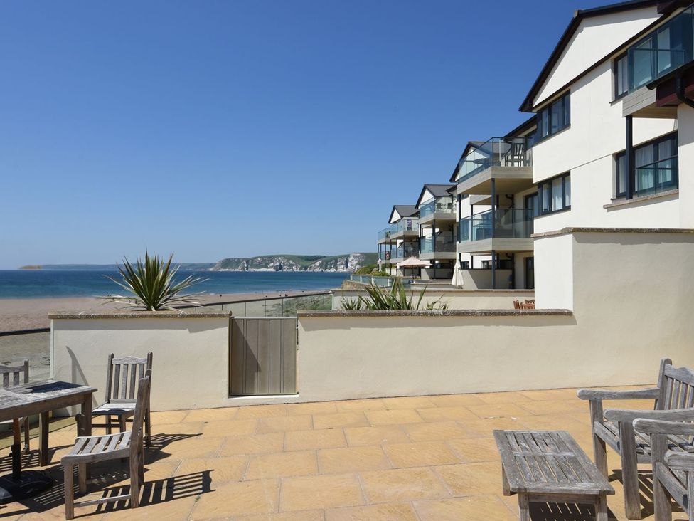 An outdoor area with a table and chairs overlooking the sea at Apartment 12, Burgh Island Causeway in Bigbury-On-Sea