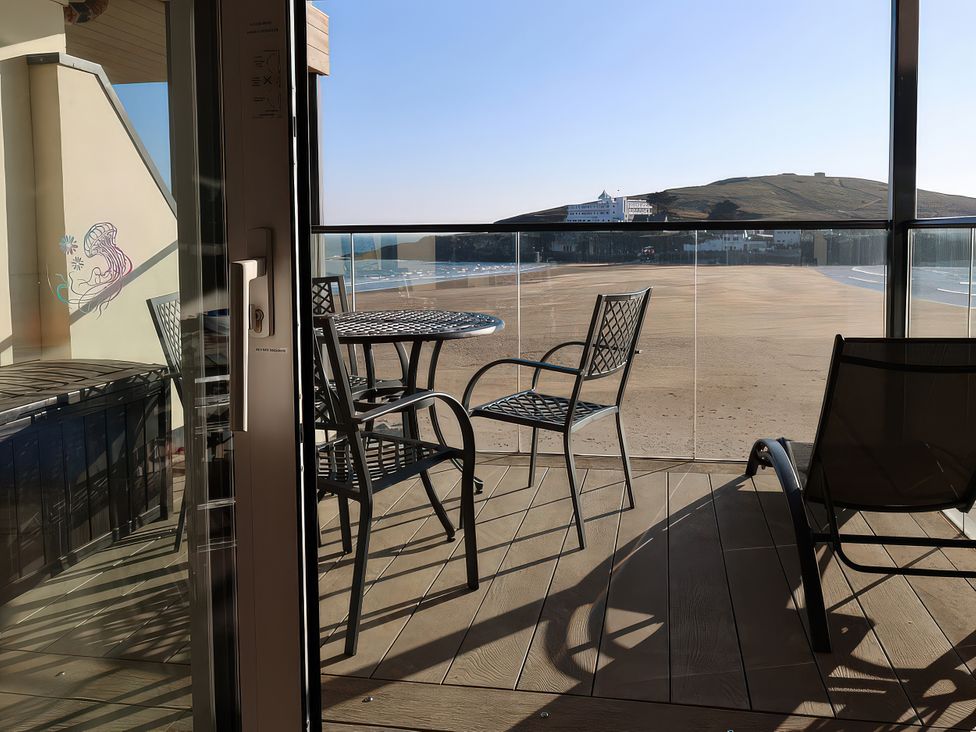 A balcony with chairs and a table overlooking the beach at 12 Burgh Island Causeway Bigbury-On-Sea