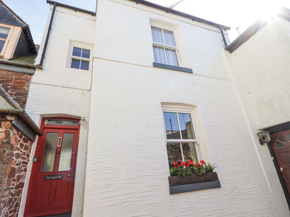 An exterior view of a white house with a red door and flower box at Springfield in Kingsand