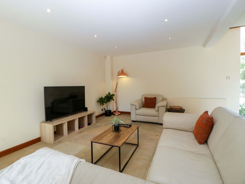 A living room with a sofa, coffee table, and television at Heathcliffe House, Castleton near Cardiff
