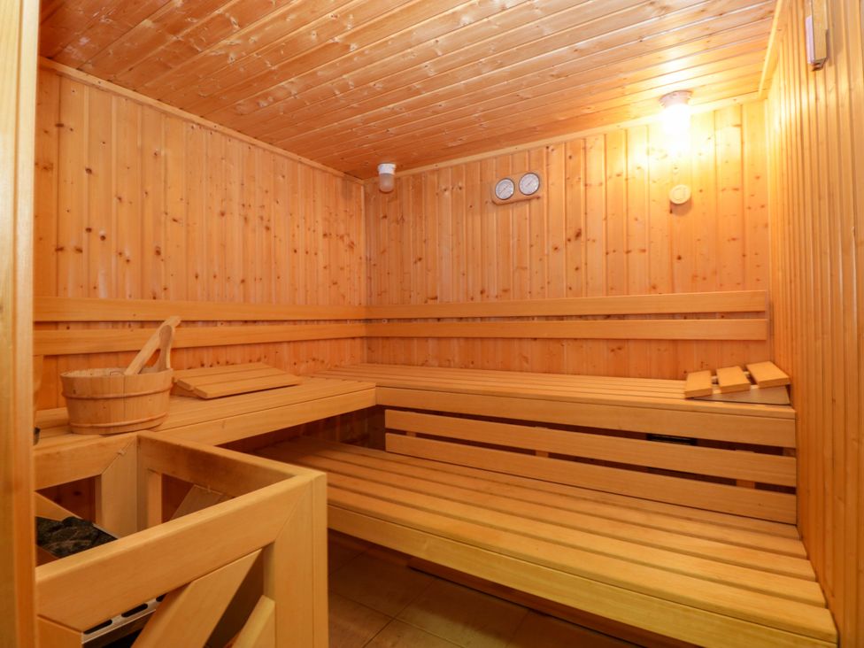 A sauna with wooden benches and a bucket at Heathcliffe House in Castleton near Cardiff